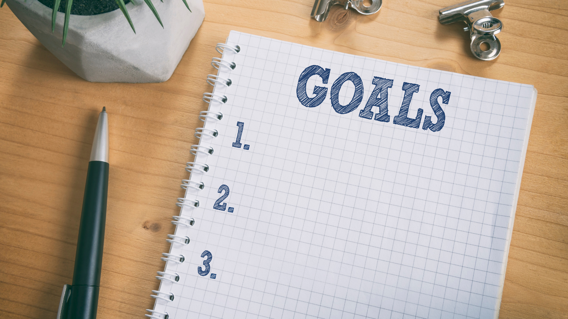 Goals notebook on desk with pen showing numbered list for planning